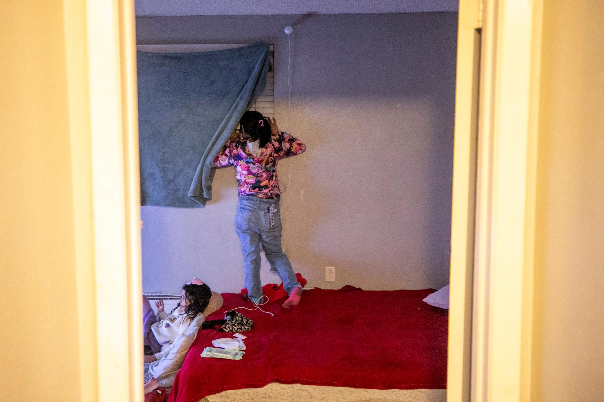 An immigrant from Venezuela peeks out of a window to check for police.